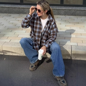 Camicia a quadri da donna con jeans blu a gamba larga in un look di moda urbana all'aperto