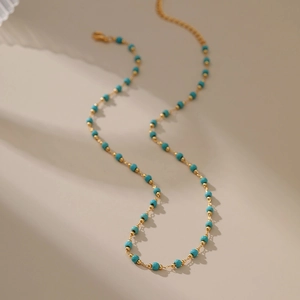 18K gold plated copper necklace with turquoise beads shown on a warm minimalist background