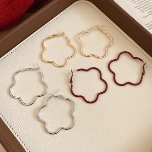 Detail of vintage hollow flower hoop earrings in gold, silver and wine red finishes