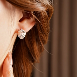 Close-up of strawberry-shaped earring with pink and clear crystals on model ear