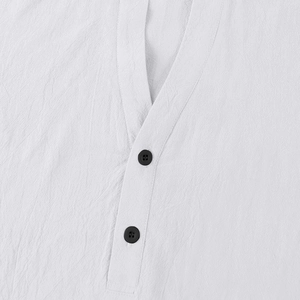 Detailed view of the white linen fabric texture and black buttons on the v-neckline