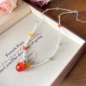 Détail d'un collier de perles avec pendentif cœur rouge dans une boîte en bois