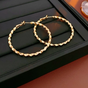 Macro detail of golden irregular round earrings featuring a sparkling diamond-cut texture