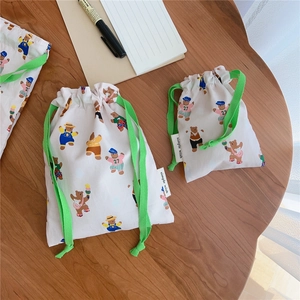 Detail view of two bear print cotton drawstring storage bags on a dark wooden table