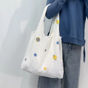 Detail of soft lamb-like fleece tote bag with blue and yellow embroidered star patterns