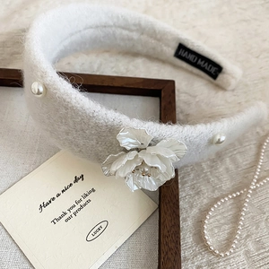 Detail of plush floral headband with pearls and handmade label on soft fabric
