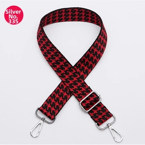 Close-up of red and black houndstooth pattern bag strap with silver metal hooks