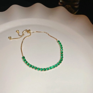Close-up of golden adjustable slider bracelet with sparkling round green zircon stones