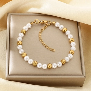 Detail eines eleganten Perlenarmbandes mit Goldperlen auf champagnerfarbener Seide