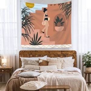 Detail of Bohemian tapestry with minimalist woman illustration hung above a cozy bed frame