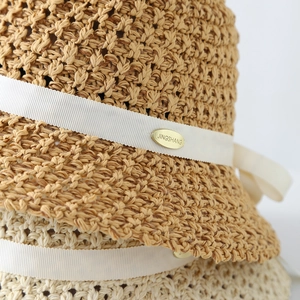 Détail de la texture d'un chapeau de paille tissé à la main avec plaque dorée