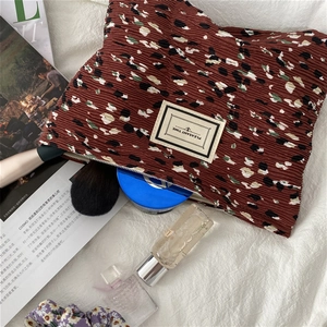 Close-up of pleated floral cosmetic bag with 'PLEASANT TIME' label and secure zipper