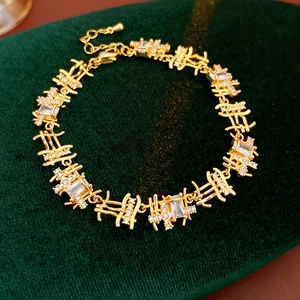 Détail d'un bracelet doré avec des maillons en zircone sur du velours vert