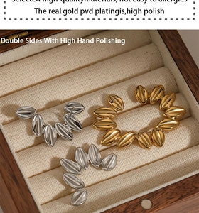 Detailed view of three PVD gold plated leaf shaped ear cuffs on a beige velvet jewelry tray