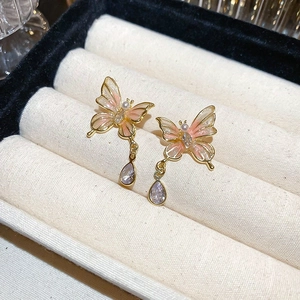Détail de boucles d'oreilles papillon avec émail rose et pendentif en cristal violet