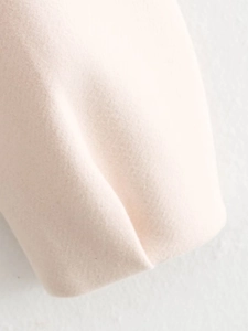 Close-up of light pink wool blend fabric texture showing fine stitching and soft material