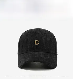 Detail view of the heavy twill wool fabric and golden metal letter C on the baseball cap