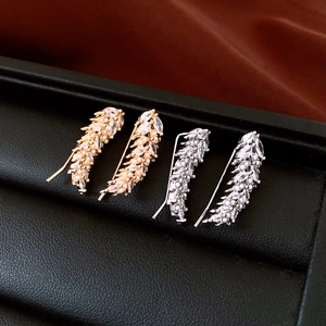 Macro shot of gold and silver wheat feather ear cuffs with cubic zirconia and white pearls