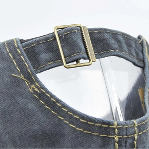 Detailed close-up of adjustable bronze metal buckle and contrast stitching on cotton baseball cap