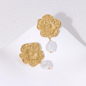 French retro gold flower earrings with baroque pearls on a minimalist white stone pedestal
