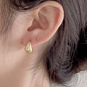 Close-up of elegant gold teardrop earrings with shimmering stones worn on a model