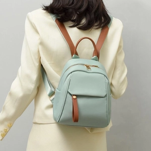 Elegante zaino in nylon verde chiaro con dettagli in pelle marrone indossato da modella