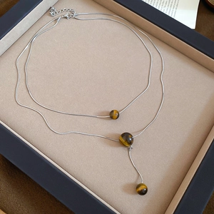 Close-up of double-layered silver necklace with three polished tiger eye stone beads