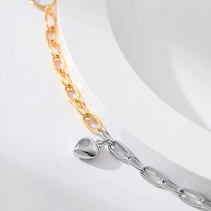 Macro shot of gold and silver chunky chain bracelet with heart pendant and OT clasp