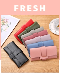 Flat lay of multiple long textured leather wallets with buckle straps on a wooden table