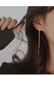 Close-up of elegant gold long tassel chain earrings worn by a model for a chic look
