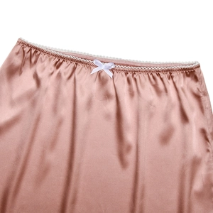 Détail d'une jupe en satin rose avec bordure en dentelle blanche et petit nœud élégant