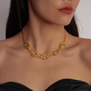 Détail d'un collier vintage doré avec pendentifs en spirale porté par un mannequin