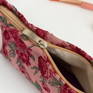 Detail of vintage floral embroidery and premium gold metal zipper on travel makeup bag