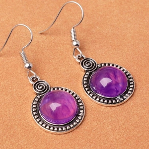 Détail macro de boucles d'oreilles vintage argentées avec résine violette et spirales