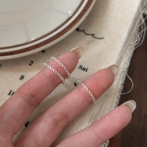Close-up of three 925 sterling silver heart-shaped hollow rings layered on a finger