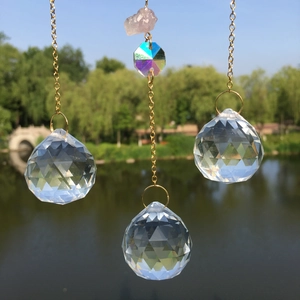 Hanging crystal suncatcher with pink quartz and faceted crystal balls against a lake view