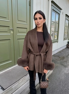 Detail of dark brown wool coat featuring plush fur cuffs and a self-tie waist belt