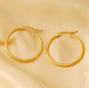 Detailed close-up of gold titanium steel hoop earrings with textured thread design