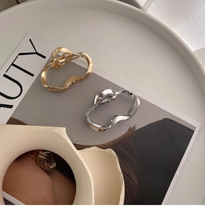 Close-up of minimalist wave-shaped gold and silver metal hair claws with mirror finish