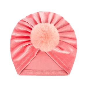 Close-up of pink velvet baby beanie with soft faux fur pompom and detailed fabric texture
