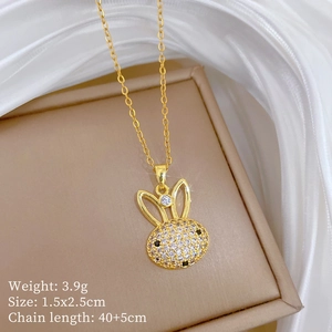Détail macro du pendentif lapin doré avec cristaux sur fond de soie, taille 1.5x2.5cm