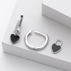 Detailed macro view of 925 silver heart lock earrings with black enamel and diamonds