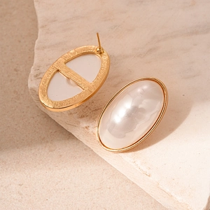 Close-up of oval vintage gold earrings with silk texture pearls on stone surface