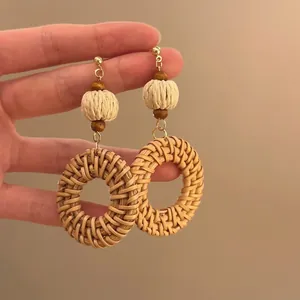 Close-up of bohemian woven rattan circle earrings with wooden beads and metal hooks
