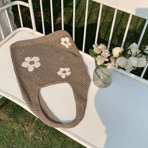 Detail einer handgestrickten Tragetasche mit Blumenmuster auf einer Gartenbank