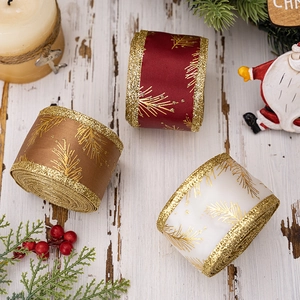 Red gold and white Christmas ribbons with pine needle glitter patterns on wood surface