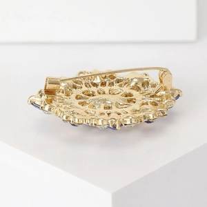 Vintage gold oval rhinestone brooch showing intricate filigree metalwork and pin fastening