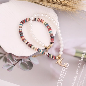 Detail of dolphin charm bracelet set with colorful heishi beads and pearls in shell tray
