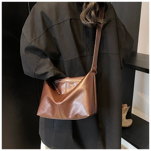 Detail of dark brown leather tote bag showing glossy texture and decorative stitching