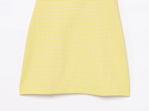 Detailed close-up of yellow and white gingham seersucker fabric texture on the dress hem